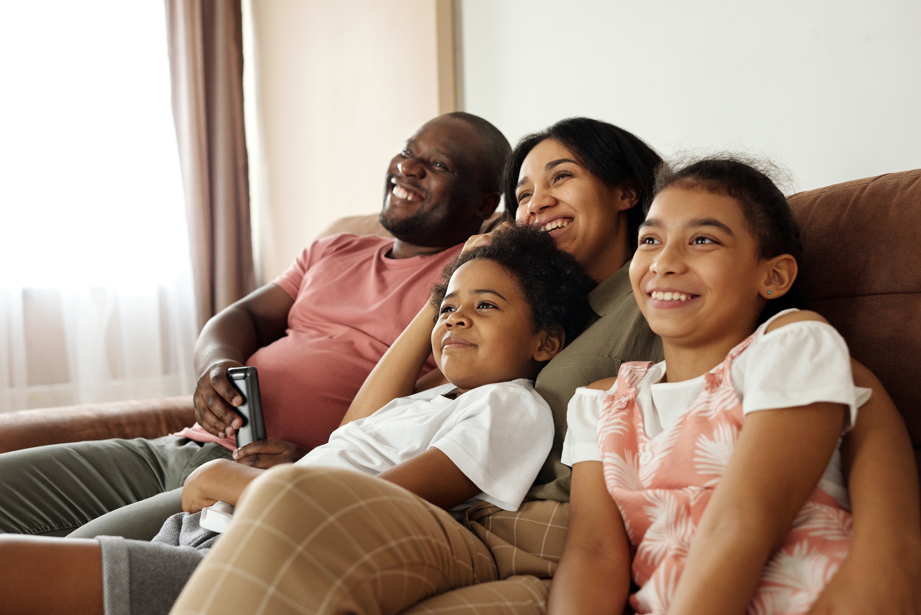 happy family sitting on a couch and watching tv 4260639 — happiness happiness